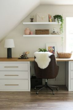 an image of a home office with white cabinets and shelving on the wall above it