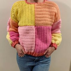 a woman wearing a multicolored crochet sweater with her hands in her pockets