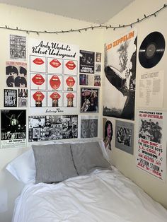 a bed with white sheets and posters on the wall above it, along with vinyl records