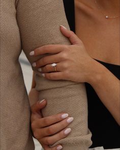 a woman with her hands on the arm of another person wearing a ring and sweater