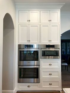 a kitchen with white cabinets and stainless steel ovens