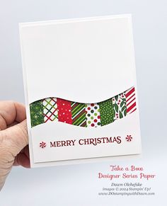 a hand holding up a christmas card with the words merry christmas written on it in red, green and white