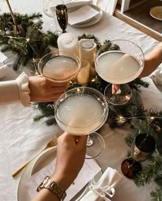 two people holding champagne glasses at a table with christmas decorations on the table and candles in front of them