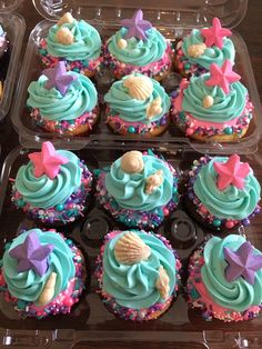 cupcakes with blue frosting and pink sprinkles in a plastic container