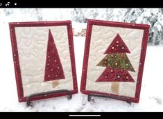 two red and white quilted christmas trees sitting on top of snow covered ground