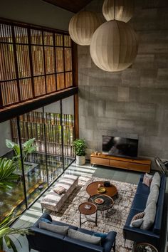 a living room with couches, tables and lamps hanging from the ceiling in front of a flat screen tv