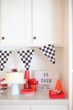 a birthday party with cars and race flags on the wall above the cake, along with other desserts