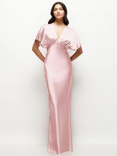 a woman in a long pink dress standing with her hands on her hips and looking off to the side