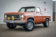 an orange pick up truck parked in front of a building