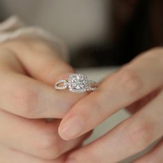 a woman's hand holding an engagement ring with two diamonds on top of it