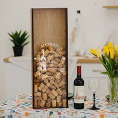 there is a wine bottle and two glasses on the table with flowers in vases