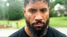 a close up of a person with a beard wearing a black shirt and looking at the camera