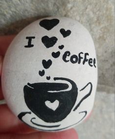 i love coffee painted on a rock in someone's hand with hearts coming out of it