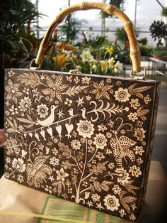 a brown and white purse sitting on top of a wooden table next to some flowers