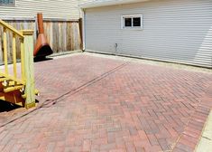 a brick patio with steps leading up to the back door and garage in the background