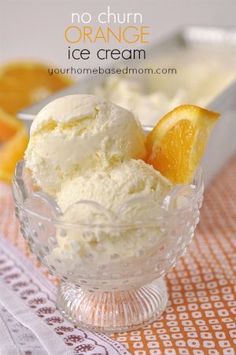 an orange ice cream in a glass bowl with two slices of orange on the side