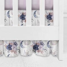 a white crib with blue and pink flowers on it