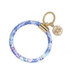 a keychain with a blue and white flower design on the front, hanging from a gold plated metal hook