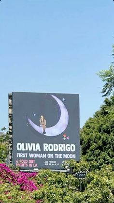 an advertisement for the first woman on the moon is displayed in front of some trees