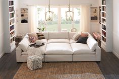 a living room with white couches and lots of books on the shelves in it