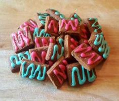 a pile of cookies with pink and blue frosting on them sitting on top of a wooden table