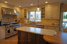 a large kitchen with an island in the middle and stainless steel appliances on both sides