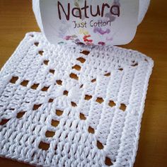 a white crochet doily sitting on top of a wooden table next to a roll of yarn