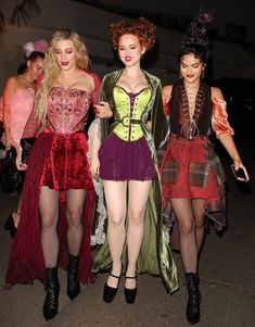 three women dressed in costumes walking down the street