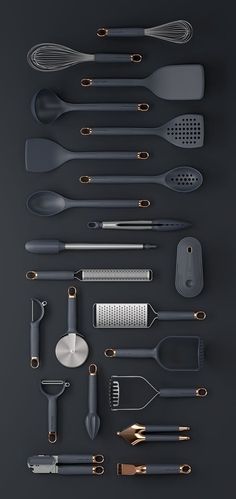 an assortment of kitchen utensils arranged on a black surface with gold trimmings