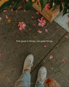 someone is standing on the sidewalk with their feet up in front of some pink flowers