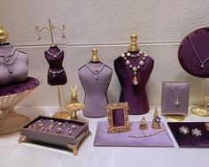 a table topped with purple mannequins and jewelry