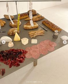 a table topped with lots of different types of breads and meats on top of it