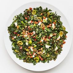 a white plate topped with lots of green vegetables and toppings on top of it