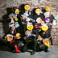 a group of people with faces painted on them posing in front of a brick wall