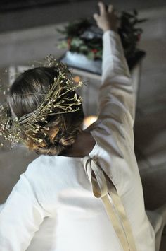 a woman wearing a white shirt and gold ribbon around her neck is reaching up into the air