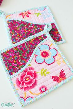 two quilted pot holders sitting on top of a white table next to each other