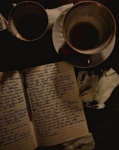 an open notebook with writing on it next to two cups of coffee