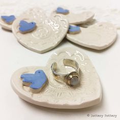 two heart shaped buttons with blue birds on them sitting next to each other in the shape of hearts