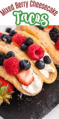 mixed berry cheesecake tacos with whipped cream and fresh berries on top, sitting on a black slate platter