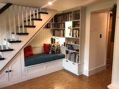 there is a book shelf under the stairs in this room with bookshelves on both sides