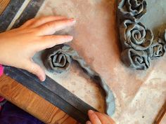 someone is working with clay to make roses in the shape of heart and flower buds