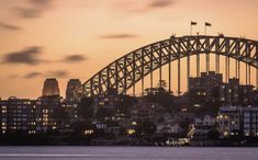 the sydney harbour bridge is lit up at night, with buildings in the foreground