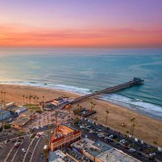 an aerial view of the beach and pier at sunset