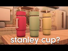 three different colored cups sitting on top of a wooden table next to a tv screen