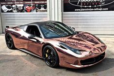 a copper colored sports car parked in front of a garage door with two large doors