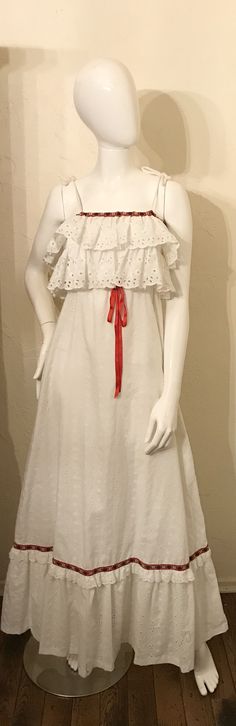 "Here is a sweet 1970's dress for Summer. It is a white cotton eyelet in a maxi length. It has the ruffles at bust and hem with the cute red embroidered ribbon trim. There are tie shoulder straps and an elastic empire waist. It is lined and has a nylon zipper in back. Tagged - Vicky Vaughn Juniors Condition - good, some faint soiling along hem fold Measurements lying flat across: Bust 17\", Empire waist 10-15\", Hips 25\", Length 59\", Mannequin is 34-25-36" White Ruffled Prairie Dress For Spring, White Prairie Dress With Ruffles For Spring, Vintage White Maxi Dress With Ruffles, White Cotton Prairie Dress With Ruffles, Embroidered Ribbon, Ruffle Maxi Dress, 1970s Dresses, Dress For Summer, Sequin Party Dress