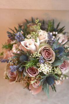 a bridal bouquet with pink roses and blue thistle