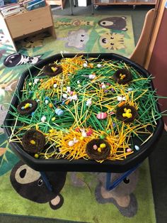 a black tray filled with fake grass and small candies in it's center