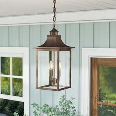 a light hanging from the side of a house next to a potted plant and window