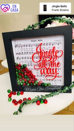 a framed christmas card with red and green ornaments on it, next to a sheet of music